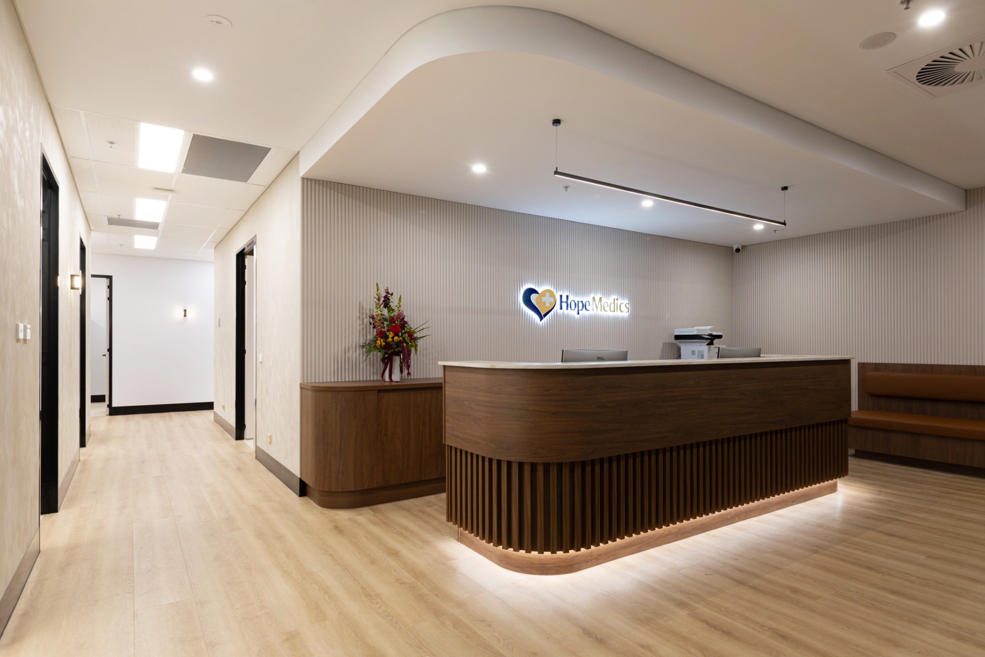 Warm timber reception desk with flowers and soft lighting